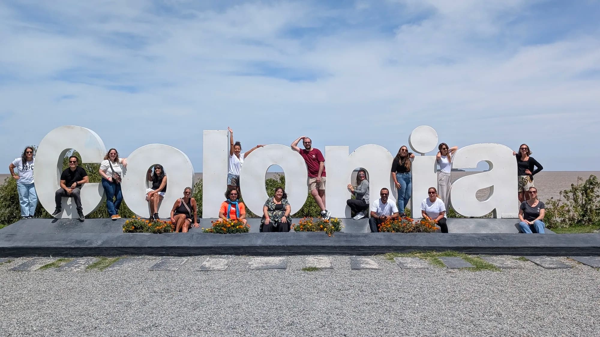Grupo de AV Business & Communication sentado en las letras de Colonia, Uruguay