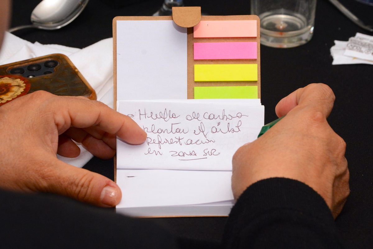 Manos escribiendo una meta corta a mano en una libreta durante una capacitación